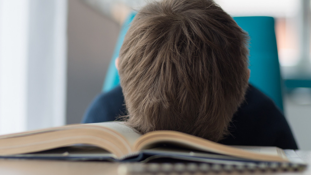 Niño con dificultad para leer mientras estudia con un libro